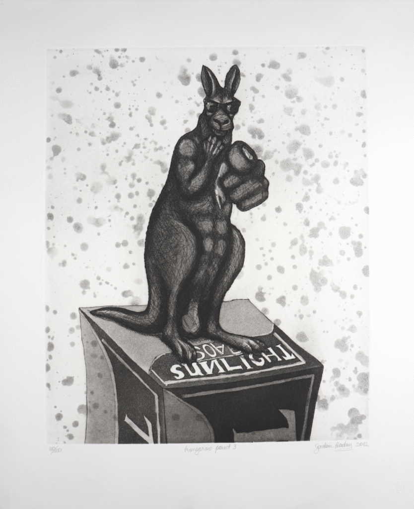 Dark, muscular kangaroo statue wearing sunglasses stands on a display box, pointing directly at the viewer against a speckled background.